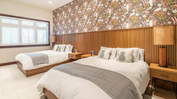 Light-filled guest bedroom with twin beds, linen bedding, and a botanical accent wall